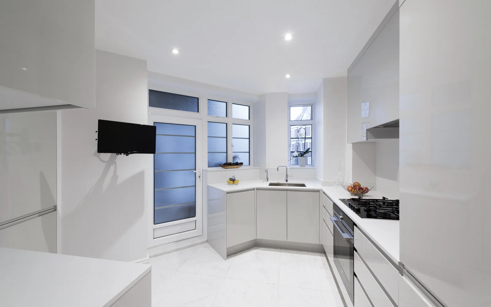 Modern white handleless fitted kitchen with integrated appliances installed by Form & Frame